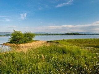 Fototapeta na wymiar Douglas Lake in the spring in Tennessee with the Great Smoky Mountains in the background, the water and sandy shore with a blue sky filled with clouds in the distance.