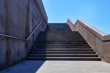 Wide stone staircase. Way up to blue sky in sunny day. Concept of hope and bright future. Freedom, career or success concept. Granite stairs.