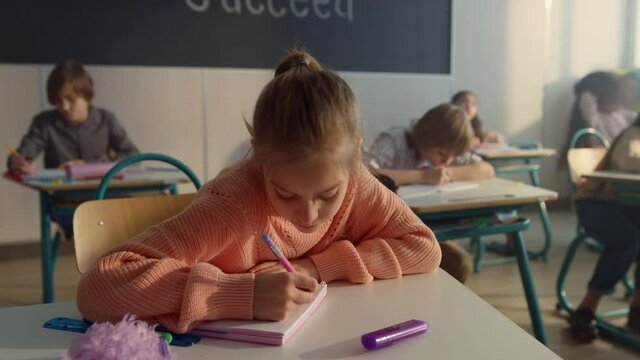 Schoolgirl making notes in notebook. Smart student writing in exercise book