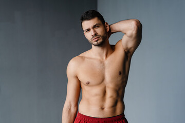 Fototapeta premium Young shirtless sportsman doing exercise while working out indoors