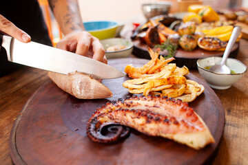 chef cutting grilled fish on table on seafood barbecue