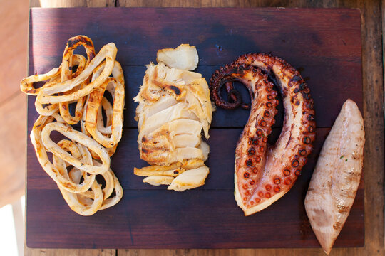 grilled seafood octopuss squid and fish on wood cutting board