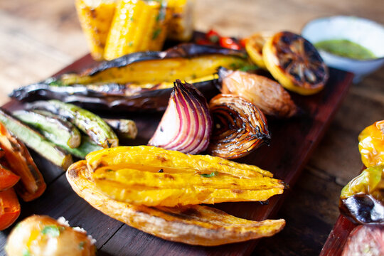 roasted griled  banana onions and vegetables on display on a wooden cutting board