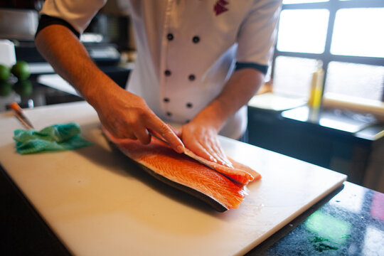 sushiman preparing salmon with a knife on a restaurant
