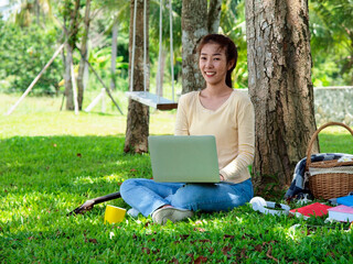 Asian student girl is studying  online by laptop in garden. Asian student is happy in study online....