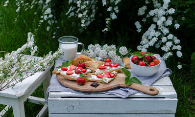 Board of food with delicious dessert and milk for breakfast on a wooden box in the garden with...