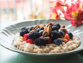 Delicious breakfast oat porridge on plant milk with nuts and berries on marble table