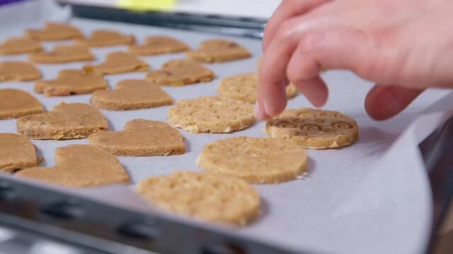 A woman lays out cookies for baking on a baking sheet. 4K.