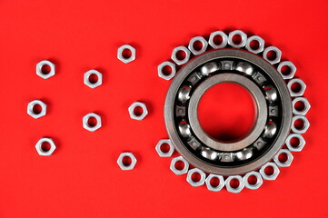 Roller bearing and nuts on a red background. Spare parts.