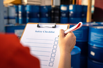 Action of factory supervisor is using a pen to checking on safety checklist form, with blurred...