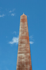 Iron obelisk with a small cross on a street in Madrid. Spain