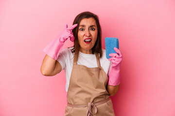Middle age caucasian woman cleaning home isolated on pink background showing a disappointment gesture with forefinger.