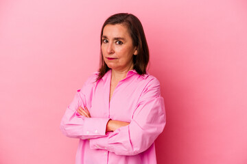 Middle age caucasian woman isolated on pink background suspicious, uncertain, examining you.