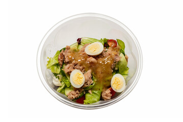 Fresh tuna salad with lettuce, cucombers, cherries and eggs in plastic container.
