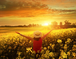 Naklejka na ściany i meble Happy woman enjoys beautiful sunset on flower field