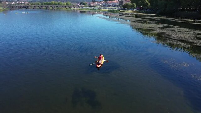 couple in a relaxing moment of a summer day taking pictures of Ponte de Lima in Portugal while paddling together in a kayak on the Lima River
