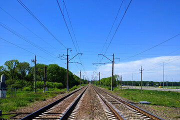 Fototapeta na wymiar Railway railroad tracks rails wires poles at large city station a bright summer day