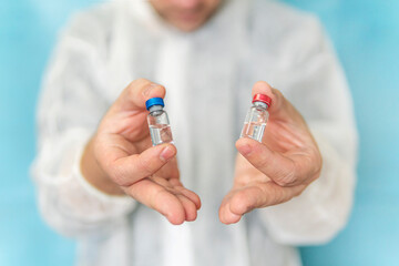 The doctor holds in his hands 2 ampoules to choose from. Choosing best vaccine. The nurse gives the...