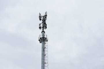 Cell tower on background of gray sky.