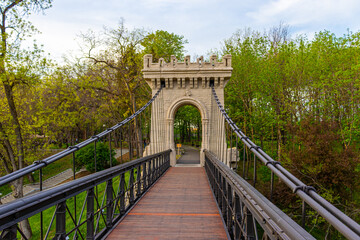 Photography of a suspended bridge over the river in the park in Craiova, Romania.