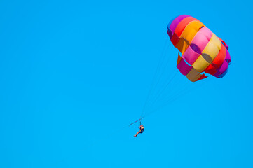 Parasailing on blue sky. Copy space, holiday fun activities. Couple under parachute hanging mid air. Positive human emotions, feelings, family, travel, vacation. Sea summer recreation background.