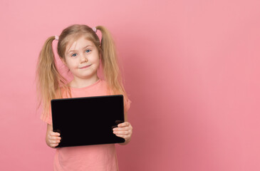 Happy child showing tablet computer with copy space on pink background.