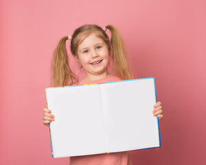 Smiling girl showing open book with empty copy space over pink background. Education concept.