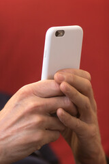 main tenant un téléphone portable blanc sur un fond rouge