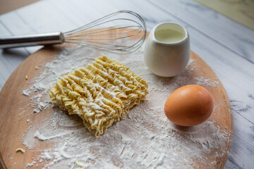 instant noodles, eggs, milk and a whisk. view from above. Selective focus