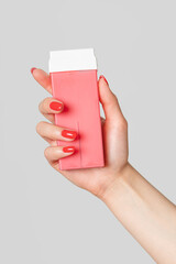 Warm wax for depilation in cassettes pink, stick in woman hand with red nails. Vertical shot...