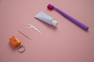 Personal oral hygiene product on a pink background. Toothbrush tube toothpaste toothpick and floss. Flat lay