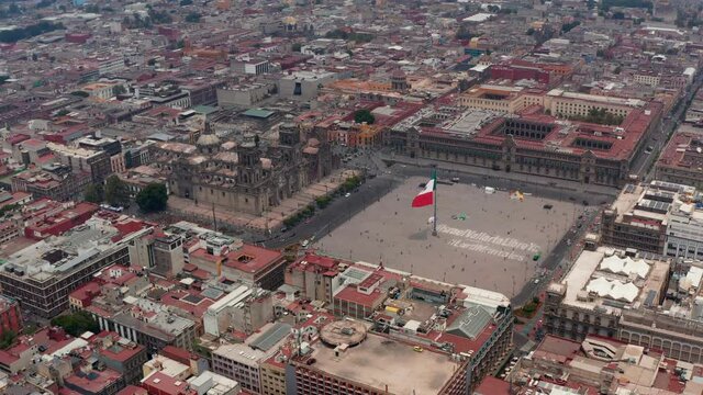 Elevated flying view of Catedral Metropolitana de la Ciudad de Mexico and Plaza de la Constitucion with huge state flag. Drone footage of historic city center. Mexico city, Mexico.