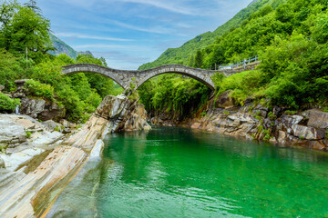 Fototapeta na wymiar View of Bridge Ponte dei Salti to Verzasca River at Lavertezzo - clear and turquoise water stream and rocks in Ticino - Valle Verzasca - Valley in Tessin - Travel destination in Switzerland