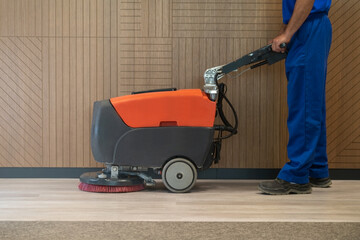 Cleaner cleans the floor with walk behind scrubber dryer machine