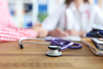 Stethoscope lies on table in background, doctor is receiving patient