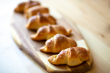 croissant, homemade fresh baked goods lies on a beautiful bamboo board on a wooden table