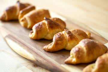 croissant, homemade fresh baked goods lies on a beautiful bamboo board on a wooden table