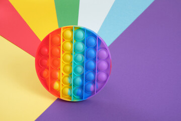 toy antistress pop it on a rainbow background, fidget toy, popping bubbles and calm down, development of the motor skills of hands and fingers - obrazy, fototapety, plakaty