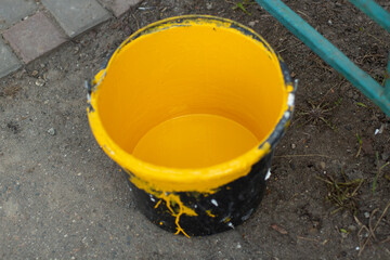 A bucket of yellow paint. Paint for painting parking posts.