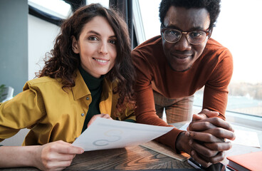 Portrait of business colleagues smiling at camera while working with documents at the table