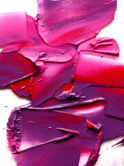 Smudged pink, red and purple lipsticks over white background