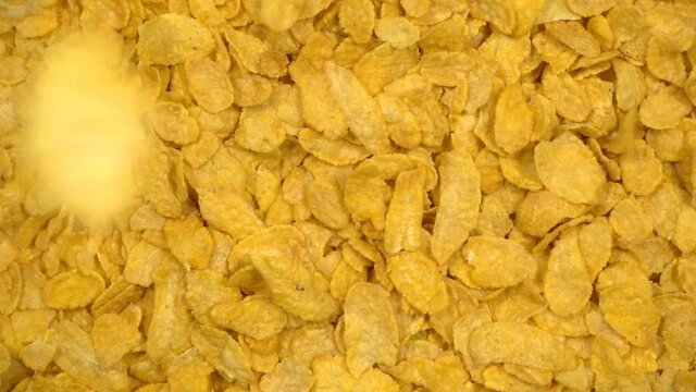 Cornflakes falling on heap of cornflakes rotating, cereal breakfast or food concept