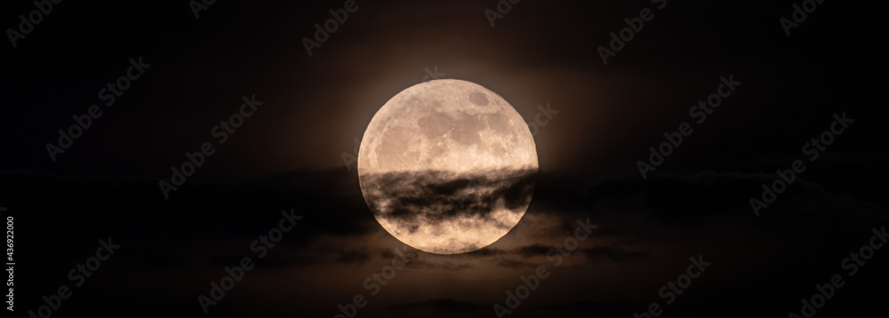Wall mural horizontal panoramic image of the full moon slightly obscured by clouds during the night
