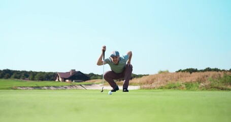 Professional man golf player wearing cap playing golf, aiming and hitting ball to camera at green golf course