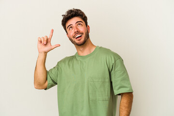 Young caucasian man isolated on white background indicates with both fore fingers up showing a blank space.