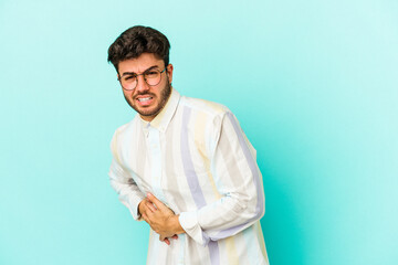 Young caucasian man isolated on blue background having a liver pain, stomach ache.