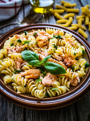 Fusilli with roasted salmon on wooden table 