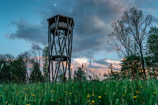 Lookout tower called Na Vetrne Horce at sunset, Broumov region,Czech Republic.Wooden tower with spiral staircase on blooming meadow fresh spring scenery.Travel explore concept.Modern architecture