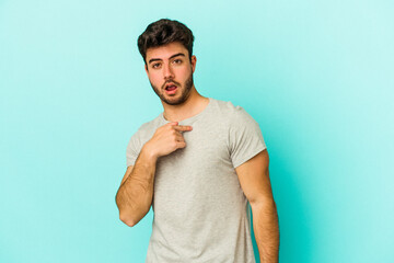 Fototapeta premium Young caucasian man isolated on blue background surprised pointing with finger, smiling broadly.