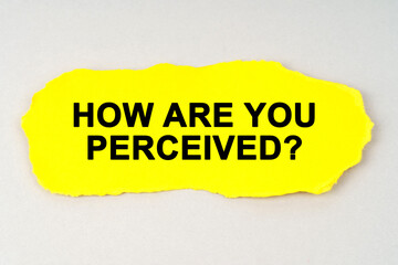 On a white background lies yellow paper with the inscription - HOW ARE YOU PERCEIVED